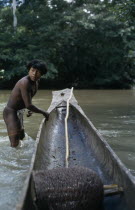 Embera man  Rio Verde  standing knee deep in water beside his wooden dug out canoe.Pacific coastal region boat piragua tribe