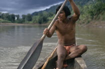 Embera man using single oar to steer wooden dug out canoe along rio Baudo.Pacific coastal region boat piragua tribe