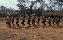 Panar men and women performing traditional dance around central area of village.  Men wearing head-dresses or crowns of feathers and face and body paint.Formally known as Kreen-Akrore  Krenhakarore...
