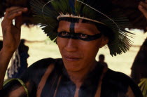 Head and shoulders portrait of young  male Panara leader wearing crown made from green parrot feathers and black face and body paint.Formally known as Kreen-Akrore  Krenhakarore  Krenakore  Krenakaro...