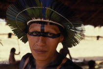 Head and shoulders portrait of young male Panara leader wearing ceremonial crown made from green/blue parrot feathers and black face and body paint.Formally known as Kreen-Akrore  Krenhakarore  Krena...