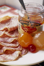 Italy, Lombardy, Cremona, Open jar of Mostarda di Cremona and salami, Type of fruit preserve spiced with mustard essential oil  also known as mostarda di frutta.