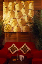 French Concession area.  Seating area in the Face Bar at the Ruijin Guest House.  Red sofa and chairs  potted plants  low wooden table and artwork on wall behind.