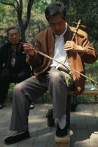Musician in Tian Tian Park playing an Erhu  traditional Chinese violin.