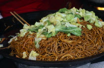 Donghua Yeshi food market.  Noodles and pak choi in wok.