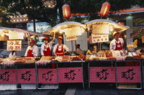 Food stalls in Donghua Yeshi night market with Chinese lanterns hanging above.