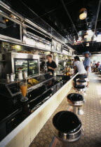 View along the bar of the Empire Diner with barman and customers