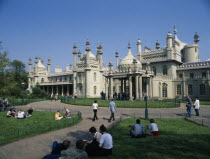 The Royal Pavilion seen from the gardens with visitors at entrance and sitting on the grassEuropean Great Britain Northern Europe UK United Kingdom British Isles History Holidaymakers Pavillion Touri...