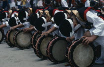 Line of bowed musicians at village festival.  In feudal times Kyushu was notable for the power of its great daimyo families and the festival celebrates the samurai with traditional dance and displays...