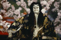 Bunraku puppet male character portraying strong emotion with a series of poses or  kata  accompanied by raised eyebrows  clenched fists and stamping feet.