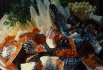 Window display of plastic food including fish and mushrooms.