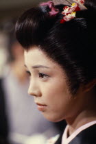 Portrait of actress in scene from popular television series set in the Edo period  1603-1868 .  Head and shoulders  three-quarter profile to left.