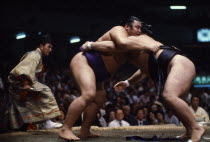 Sumo wrestlers in ring watched by referee wearing the costume of a shogun.  Sumo is an ancient form of wrestling thought to have originated in Japan some 2 000 years ago.  The ring consists of a circl...