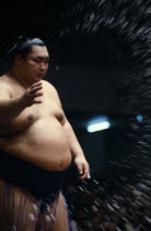 Sumo wrestler throwing handfuls of salt into the ring as an act of purification.  Sumo has close asociations with the Shinto religion with fights taking place beneath a symbolic Shinto-style roof.