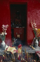 Shrine dedicated to Tin Hau  the Taoist goddess of the sea beside Aberdeen Harbour.  Statue on red altar in red painted wall niche with offerings of flowers and incense.