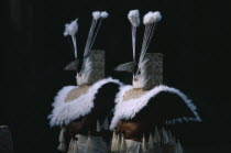 Two figures dressed in costume with woven mask and cape trimmed with white feathers for re-enactment of an ancient Tahitian coronation performed at a marae or sacrificial altar as part of Bastille Day...