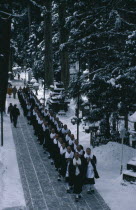 Mount Koyosan.  Centre of the Shingon Buddhist sect established by the monk Kobo-daishi.  Novice monks dressed in black and white robes filing through forest of giant Cryptomeria trees in snow to make...