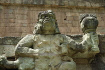 Site of ancient Mayan ruins.  Detail of statue of figure holding burning torch.