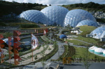 Eden Project.  General view over the Humid tropics Biome exterior with line of coloured flags and visitors on path to entrance.