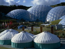 Eden Project.  General view over the Humid Tropics Biome exterior with green and white yurts in the foreground.