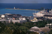 View over houses to harbour with a cruise ship at dockside and a lighthouse in the distance
