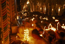 Dirwali festival  crowds of worshippers holding candles with light trails in dark temple interior.