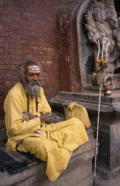 Sadhu / Holy Man sitting by a statue of Ganesh
