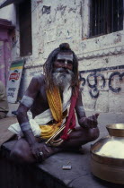 Sadhu sitting cross legged with a bugle in his lap