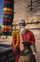 Sadhu holding a trident standing by a stupa