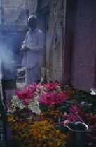 Man standing by display of flowers and burning incense