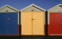 Row of three brightly painted beach huts