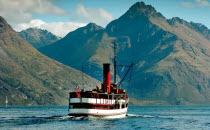 QUEENSTOWN  VINTAGE STEAMSHIP TSS EARNSALW LEAVING STEAMER WHARF AT QUEENSTOWN TAKING TOURISTS AND SAILING ON LAKE WAKATIPU WITH WALTER PEAK BEHIND.Antipodean Oceania Scenic