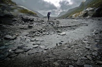 MOUNT COOK NATIONAL PARK  A WALKER CROSSES A STREAM INFRONT OF THE TERMINAL FACE OF THE FRANZ JOSEF GLACIER. Julius von Haast  geologist and explorer  named Franz Josef Glacier in 1863  after the Empe...