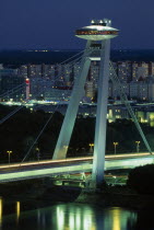 Slovakia, Bratislava, Novy Most New Bridge topped with restaurant over the River Danube with views towards Petrzalka tower blocks at night with light trails from passing traffic below.