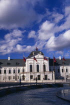 Presidential Palace  part view of exterior facade with flags.  Circular fountain in the foreground  passing people and Presidential guard either side of entrance.