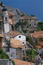 Italy, Lombardy, Lake Garda,  Limone Sur Garda, View over raised streets  church bell tower and tiled rooftops of houses with tourist vistors,  Lake partly seen beyond.