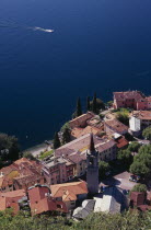 Varenna.  Looking down on red tiled rooftops  church and bell tower of town overlooking lake and distant speed boat.