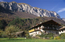 Alpine farmstead near Lago di Tenno.  Traditional building with over hanging roof and balcony  outbuildings and mountain backdrop.