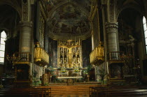 Salo.  Interior of the Duomo with ornate golden altarpiece  crucifix and painted walls and vaulted ceiling.
