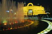 Shanghai Museum of Chinese Culture  Renmin Square.  Exterior and part view of circular fountain illuminated at night.  People standing or sitting around fountain.