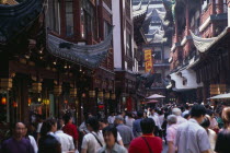Yu Gardens  Old City.  Crowds of shoppers in narrow street lined with shop fronts with pagoda style rooftops.