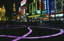 Nanjing Lu.  Street scene at night with illuminated coloured pavement trail  neon shop signs including McDonalds and crowds in blur of movement.