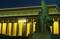 Tiananmen Square.  Mausoleum of Mao Zedong illuminated at night with statue in foreground.