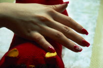 Close cropped shot of manicured and painted nails with red nail polish  white flower detail and jewel type additions.
