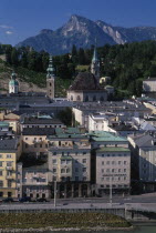 City view with Untersburg Mountain behind.  Church spire and towers and buildings with flat rooftops and roof and window balconies.