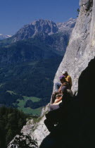 Group of hikers at cave entrance near Werfen looking out over green  wooded slopes of valley below.