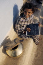 Looking down on smiling young girl using chalk to write on slate.