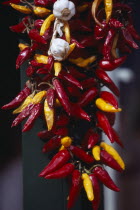 Garlic bulbs and red and yellow paprika hanging on string.