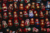 Colourful painted matryoshka dolls for sale in souvenir shop.  Displayed in lines against dark backgound.