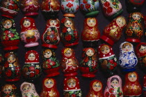 Colourful painted matryoshka dolls for sale in souvenir shop.  Displayed in lines against dark backgound.